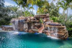 Custom luxury waterslide built into a natural rock pool with tropical landscaping and cascading waterfalls. Custom luxury waterslide built into a natural rock pool with tropical landscaping and cascading waterfalls.