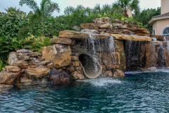 Close-up of a backyard waterslide with natural stone and lush greenery . Close-up of a backyard waterslide with natural stone and lush greenery .