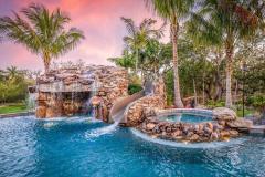 Wide-angle shot of a resort-inspired waterslide winding through custom pool landscaping. Wide-angle shot of a resort-inspired waterslide winding through custom pool landscaping.