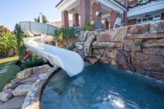 Poolside view of a slide exit area with natural rock infinity edge Poolside view of a slide exit area with natural rock infinity edge