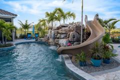 Close-up of a backyard waterslide with natural stone and lush greenery . Close-up of a backyard waterslide with natural stone and lush greenery .