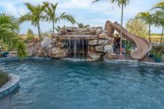 Waterslide beside a cascading waterfall feature over rugged stone accents. Waterslide beside a cascading waterfall feature over rugged stone accents.