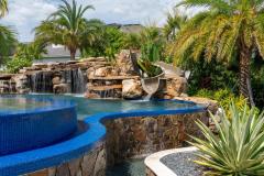 Twisting waterslide dropping into sparkling blue water with outdoor greenery backdrop. Twisting waterslide dropping into sparkling blue water with outdoor greenery backdrop.