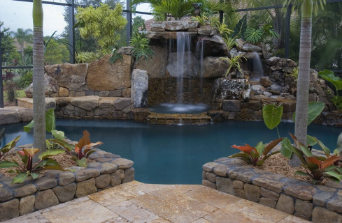 Travertine deck, stone planters and grotto waterfall