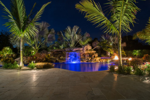 Natural lagoon pool at night with fire pits and stone grotto